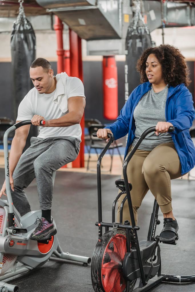 Black man and woman exercising on cycling machine